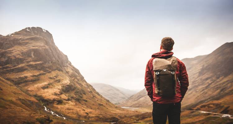 Une personne avec un sac à dos regardant un paysage montagneux spectaculaire.